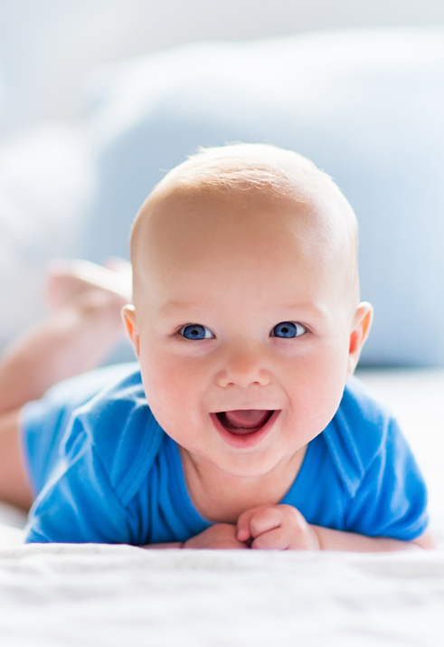 Smiling baby laying on their stomach after seeing dentist for infants in Waterford