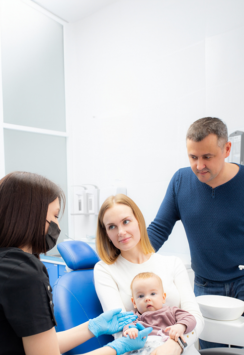 Mother holding her baby in her lap while visiting a pediatric dentist